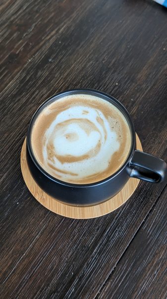 Free-pour latte art in a black ceramic cup