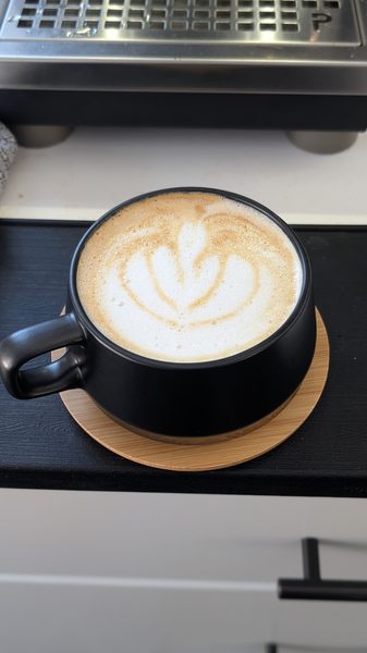 Free-pour latte art in a black ceramic cup