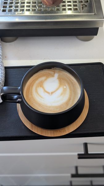 Free-pour latte art in a black ceramic cup