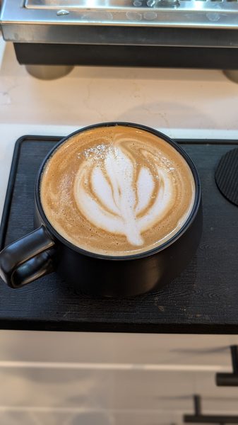 Free-pour latte art in a black ceramic cup