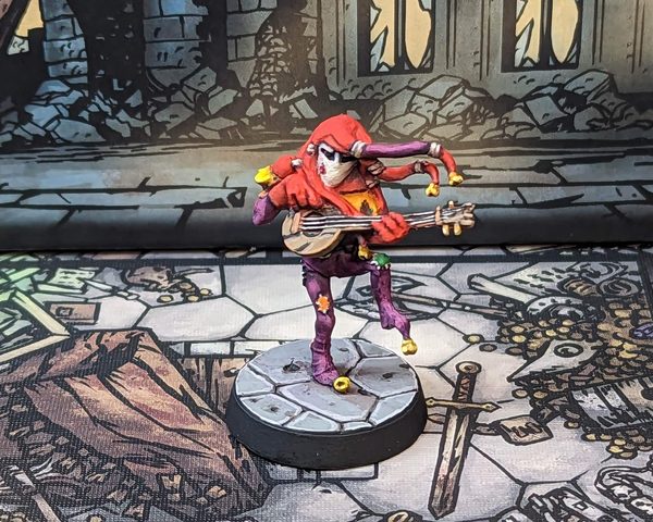 Painted Jester miniature from Darkest Dungeon: The Board Game, red and purple harlequin with mandolin